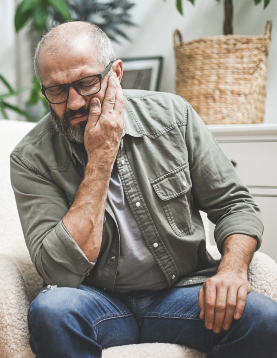 Mann fasst sich wegen störender Ohrgeräusche an die Wange.